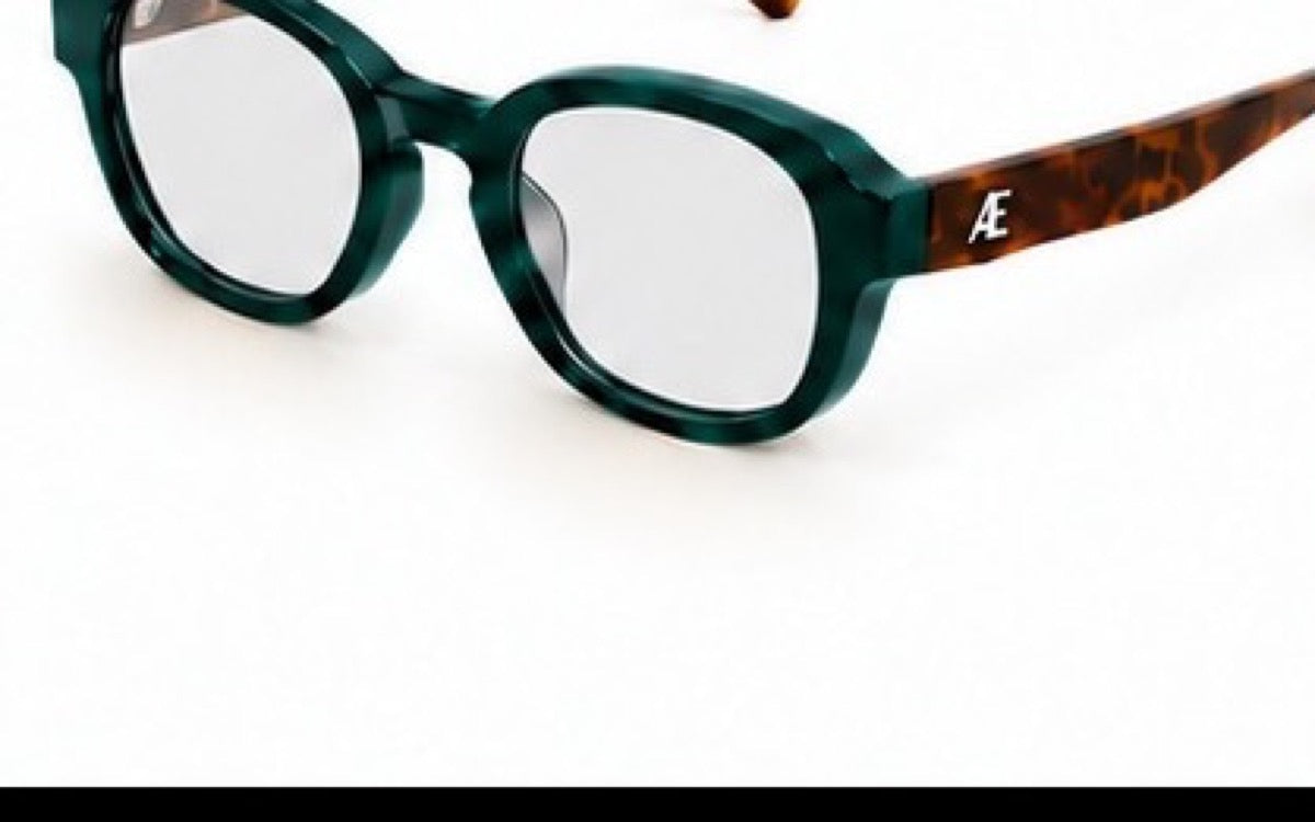 Open ATÉN Forest/Tortoise frame with Everyday Mode lenses in a cropped front-right three-quarter view; deep forest-green front, brown tortoiseshell temples and silver ATÉN monogram, on white with a thin black strip at the lower edge.