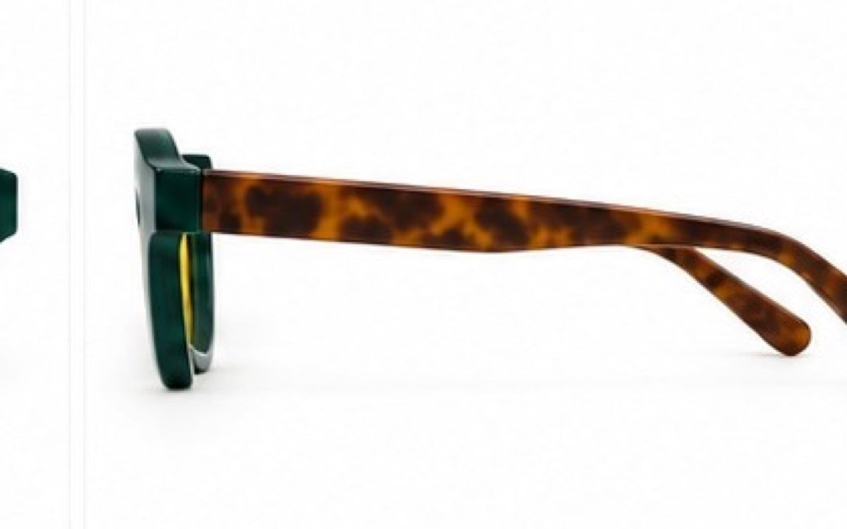 ATÉN Forest/Tortoise frame with a pronounced amber Focus Mode lens in a tight left-side profile; deep forest-green rim at left and brown tortoiseshell temples extending right, on a white background.